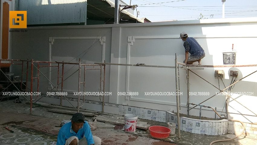 Công nhân lăn sơn nước ngoại thất của bức tường rào ngoài sân nhà