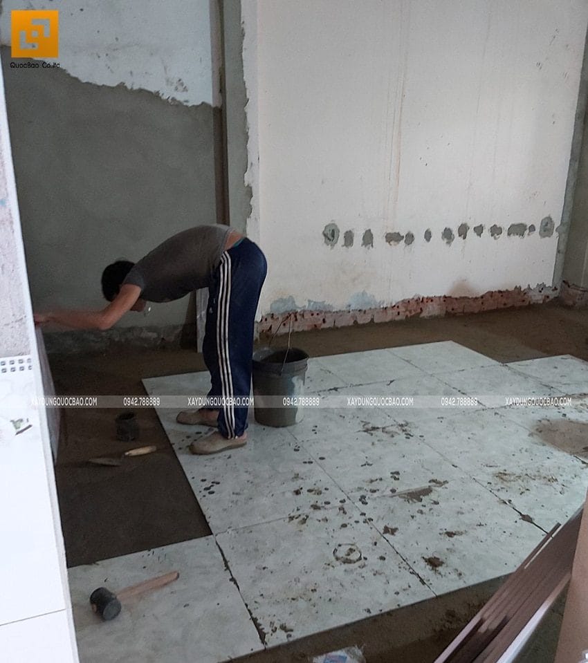 Một công nhân đang ốp gạch sàn nhà